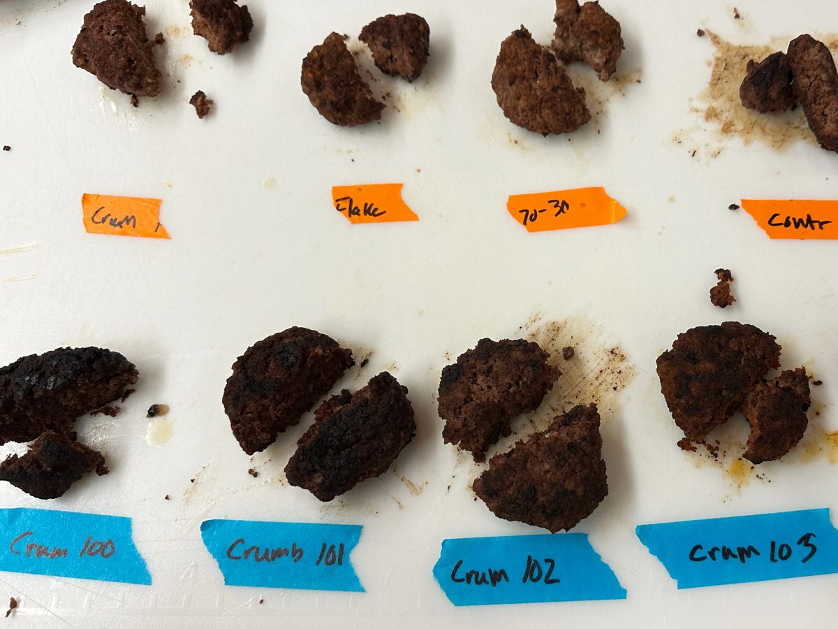 Cooked patty samples laid out on a cutting board, each labelled with its crumb variant for comparison