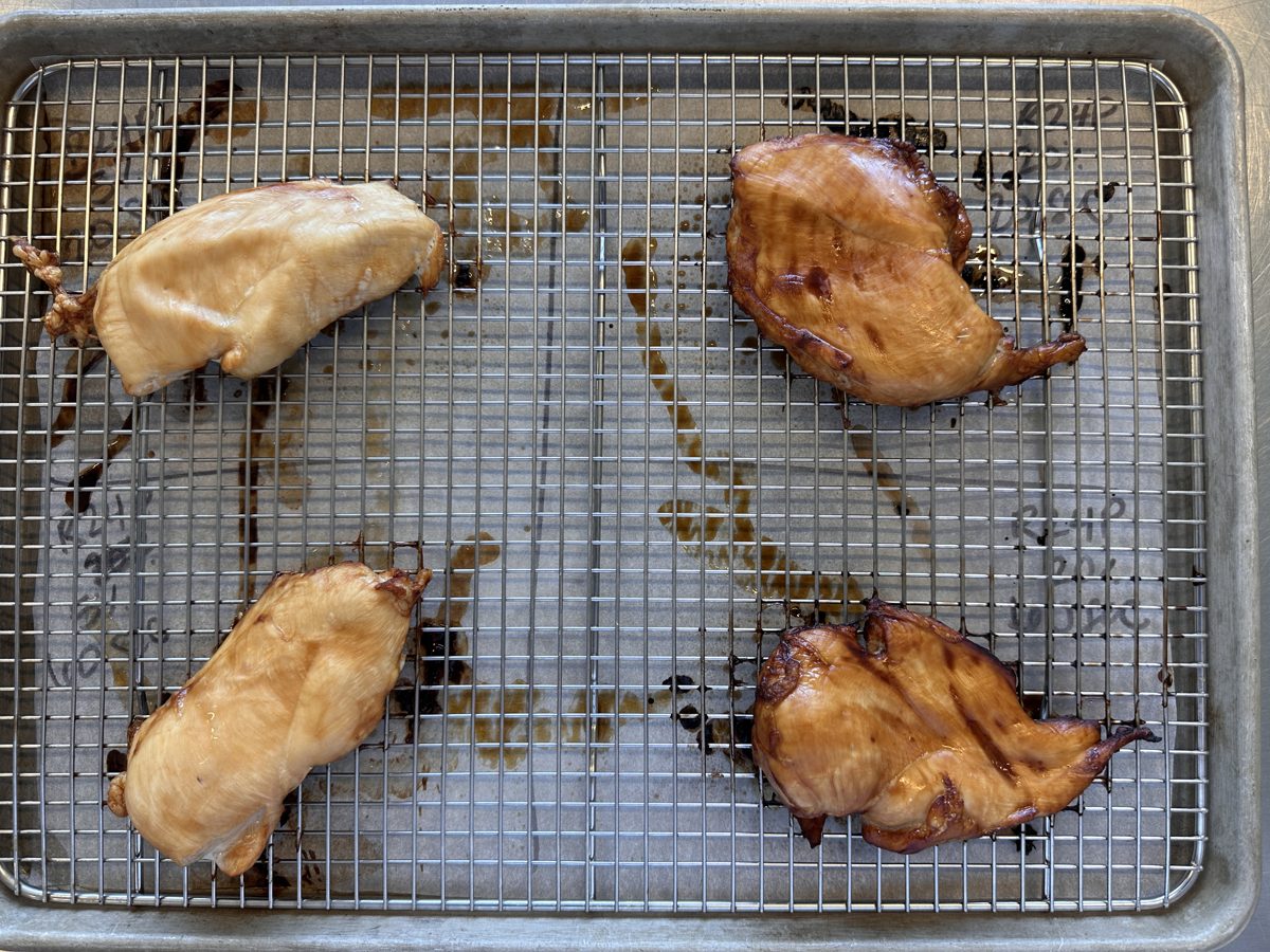 Four marinated chicken breast samples on a cooling rack after a cook test